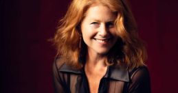 Jane Perry, known for her role as the narrator in Need For Speed: Hot Pursuit, smiles warmly in a stylish sheer blouse.