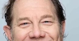 Fred Tatasciore, voice actor known for Megatron in Cybertron games, smiles warmly in a casual denim jacket.