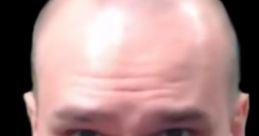 Close-up of BaldLav, the Bald Designer, focusing intently while wearing headphones against a black background.