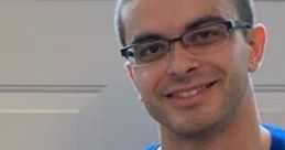 Nick Eh 30 wearing a blue shirt with his name, smiling indoors, showcasing his approachable personality.