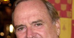 John Cleese smiling at an event, showcasing his iconic charm and wit in a black suit with a colorful tie.