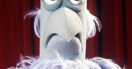 Sam the Eagle, a Muppet character by Frank Oz, displays a serious expression against a red curtain backdrop.