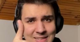Smiling young man giving a thumbs up while wearing headphones, representing positivity and engagement in streaming culture.
