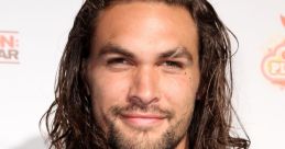 Jason Momoa smiles confidently, showcasing his long hair and stylish black shirt at a public event, exuding charisma.