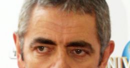 Rowan Atkinson at an event, showcasing his distinguished look with gray hair and a classic suit, reflecting his iconic style.