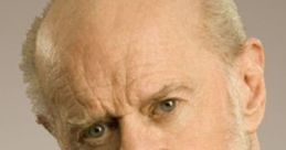 George Carlin with a serious expression, showcasing his signature wit and bold humor in a classic black shirt.