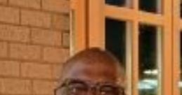Smiling man with glasses, casually dressed, posing with a group, showcasing a warm atmosphere at a social gathering.