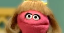 Prairie Dawn in a charming blue dress, showcasing her signature pink color and playful personality on Sesame Street.