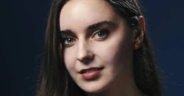Portrait of Loserfruit with long hair, wearing a colorful top and playful earrings, showcasing her engaging personality.