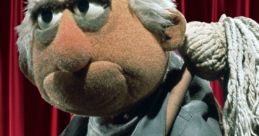 George the Janitor, a Frank Oz puppet, holds a mop, exuding a grumpy attitude against a red curtain backdrop.