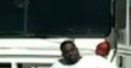 Man in a white shirt leaning against a white bus, embodying a relaxed vibe and street style associated with Jones BigAss.