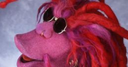 Colorful puppet character with vibrant red hair, stylish sunglasses, and a flashy outfit, embodying playful charm and creativity.