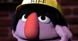 Biff, the iconic purple muppet, wearing a yellow baseball cap and a leather jacket, in a thoughtful pose.