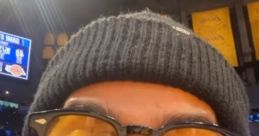 Excited fan with sunglasses and beanie shouting at a basketball game, embodying the spirit of Jamie Reyes.