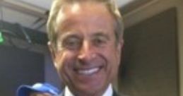Randy Hahn smiles confidently in a formal suit and tie, showcasing his charismatic presence in a broadcast setting.