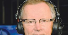 Dennis Beyak, sports commentator, wearing headphones, tailored suit, providing live hockey commentary in a broadcast studio.