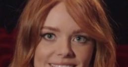 Abigail Cowen smiles brightly with flowing red hair, captivating in a theater setting.