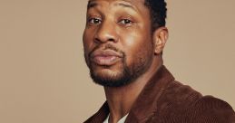 Johnathan Majors poses confidently in a stylish brown corduroy jacket, showcasing his unique fashion sense.