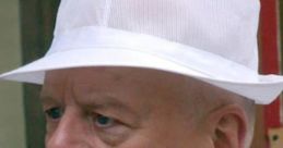 Fred Elliot from Coronation Street wearing a white hat and a floral tie, showing a serious expression.