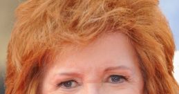 Cilla Black smiles brightly, showcasing her iconic style and vibrant red hair at a glamorous event.