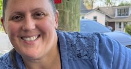Smiling woman in a blue top, representing positivity and community, enjoying time outdoors.