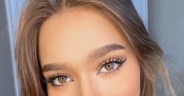 Stylish portrait of a young woman with glamorous makeup and soft waves, embodying elegance and beauty trends.