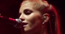 Hannah Reid performing passionately on stage, highlighting her vocal talent and stage presence under vibrant lighting.