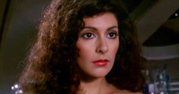 Deanna Troi in a striking off-shoulder blue dress, showcasing her signature dark curly hair and expressive features.