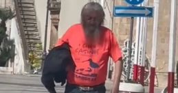 Man walking in Carovigno, wearing a bright orange shirt and jeans, showcasing local style and vibrant community life.