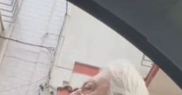 Elderly man with white hair and beard, engaged in conversation outside a car in an urban Italian setting.