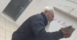 Elderly man holding a stone outside a shop, showcasing local culture in Minguccio-Mingucc, Italy.