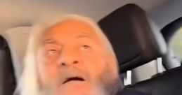 Elderly man with long white beard and surprised expression, seated inside a vehicle, capturing a candid moment.
