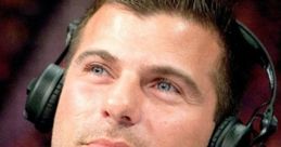 Matt Striker at the commentary table, wearing headphones and a suit, focused on the wrestling match unfolding.