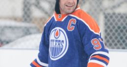 Dierks Bentley smiles while ice skating outdoors in a blue Edmonton Oilers hockey jersey on a snowy day.