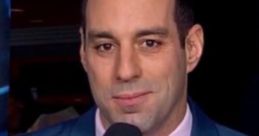 Josh Bogorad reporting for Fox Sports, with a microphone, dressed in a blue suit and pink shirt, ready to deliver sports news.