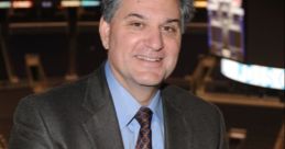 Nick Nickson smiling in a sports arena, wearing a suit and tie, showcasing his passion for hockey broadcasting.