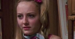 Young woman in a pink top with a stylish hair bow, showcasing a playful look reminiscent of 1980s fashion trends.