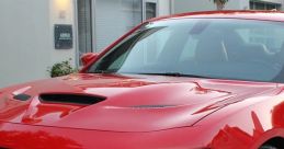Red Dodge Charger SRT showcasing sleek design, aggressive front grille, and sporty details, parked in a modern setting.