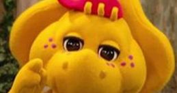 BJ from Barney & Friends, a friendly yellow dinosaur with a green belly, smiles and gestures playfully in a fun setting.