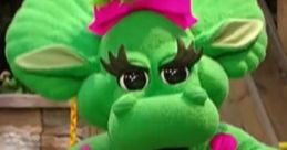 Cheerful Baby Bop from Barney & Friends, sporting a pink bow, vibrant green body, and playful expression in a fun setting.