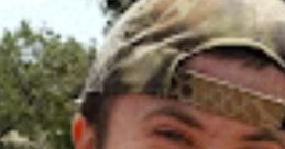 Cheerful young man wearing a camo hat and casual clothing, enjoying nature and smiling in a sunny outdoor setting.
