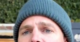 Stephen Amell with a surprised expression, wearing a blue beanie, showcasing his striking blue eyes in a casual setting.