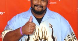 Kevin Michael Richardson smiles and gives a thumbs up while wearing a colorful shirt at a charity event.