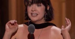 Rebecca Ford delivering an engaging speech on stage, wearing a stylish red plaid dress with a unique neckline and accessories.