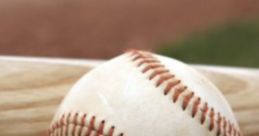 Baseball resting on green grass near a wooden bat, capturing the essence of DYB walk-up songs for players.