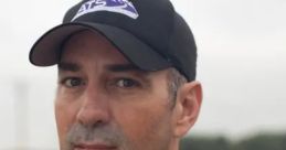Sean Casey, a storm chaser, looks focused, wearing a cap and casual shirt against a cloudy backdrop.