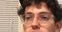 Greg from Supergenius Nerds looks contemplative while wearing a cap and glasses, seated against a casual background.