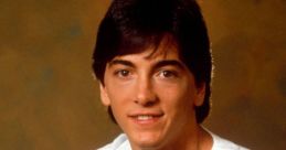 Scott Baio, star of "Charles in Charge," smiles warmly in a casual white shirt, showcasing 80s pop culture style.