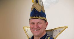 PRINS_JULIUS in traditional royal attire, featuring a ornate blue costume and feathered hat, holding a royal scepter.