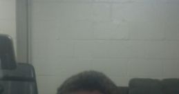 Casual portrait of a young man with short hair, sitting in front of a computer in a simple indoor space.